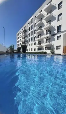 a large swimming pool in front of a building at Cozy appartement avec piscine in Bouznika