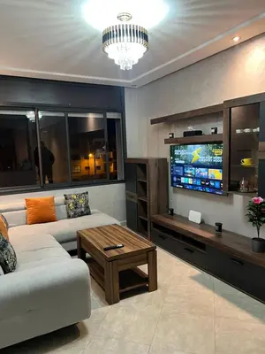 a living room with a couch and a tv at Cozy appartement avec piscine in Bouznika