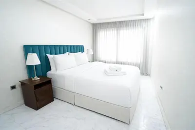 a bedroom with a large white bed and a window at Studio Paisible aux Hopitaux Wifi & Parking in Casablanca