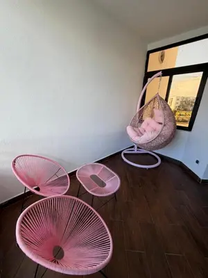 a room with three pink chairs and a swing at Charming 3 bedroom with pool in the building in Casablanca