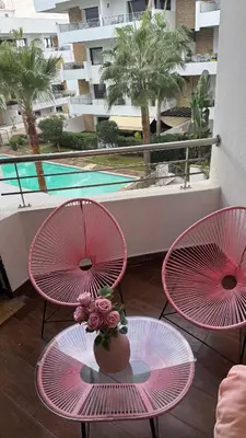 three pink chairs and a table with a vase with flowers at Charming 3 bedroom with pool in the building in Casablanca