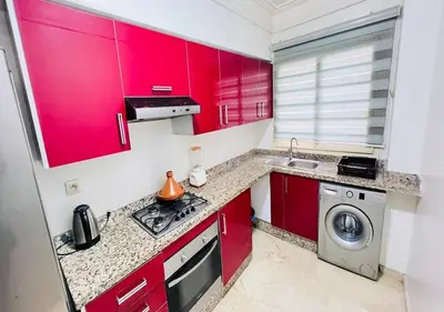 a kitchen with red cabinets and a washing machine at Familly Residence in Casablanca