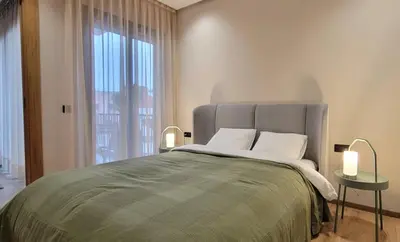 a bedroom with a bed with two lamps and a window at Appartement moderne avec parking, toit terrasse et salle de sport - Anfa Park in Casablanca