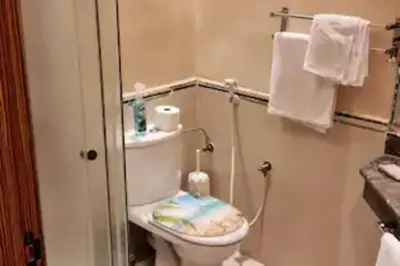 a bathroom with a toilet and a sink and towels at Casablanca !Tamaris! 2 bedrooms! Pool & Sea View! in Dar Sidi Slimane