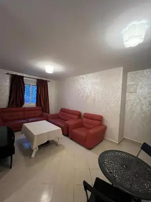 a living room with a red couch and a table at 2 Bedrooms 3 beds and a living room in Dar Bouazza in Dar Ben Abdallah Ben Dehbi