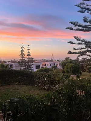 a sunset view from the backyard of a house at Harhoura Sea view apartment with green spaces and a pool in El Harhoura