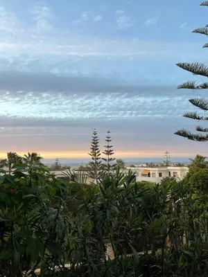 a view of the sunset from the beach with plants at Harhoura Sea view apartment with green spaces and a pool in El Harhoura