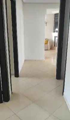 a hallway with a white tile floor and an open door at Garden Beach in Sidi Rahal