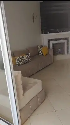 a living room with a brown couch and a fireplace at Garden Beach in Sidi Rahal