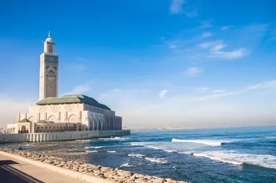 a building with a clock tower next to the ocean at Beach Ain Diab - Beautiful Apt in Bourgogne in Casablanca