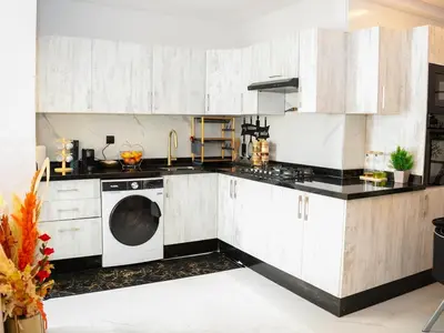 a kitchen with white cabinets and a dishwasher at Bel appartement, piscine intérieure et extérieure in Temara