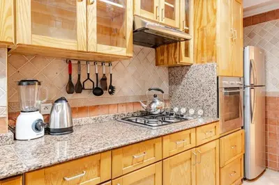 a kitchen with wooden cabinets and a stove top oven at Moderne, 2 CH, Fibre optique, AC Garage Ascenseur in Rabat