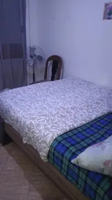 a bed with a white comforter and a chair at Belle chambre sidi maarouf in Casablanca