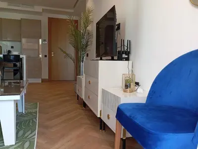 a living room with a blue chair and a tv at Les princesses studio confortable in Maarif