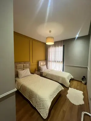 two beds in a room with a window at Appartement convivial in Rabat
