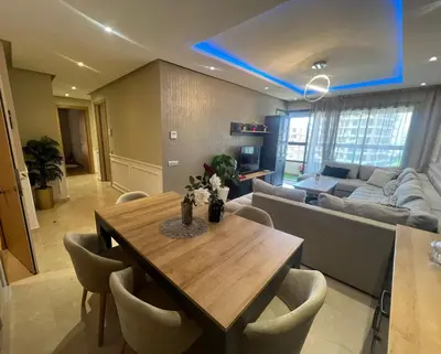 a living room with a table and a couch at Appartement convivial in Rabat