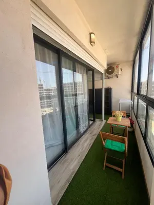 a balcony with a table and a chair and windows at Appartement convivial in Rabat