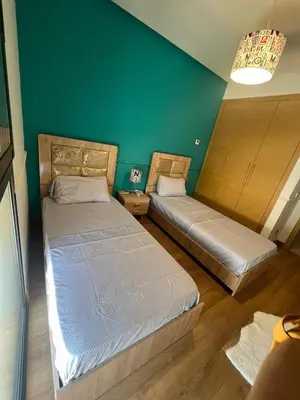 two beds in a room with a green wall at Appartement convivial in Rabat