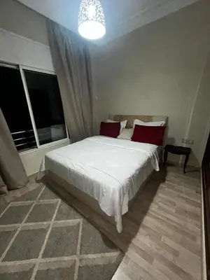 a bedroom with a large white bed with red pillows at Cozy Apt Near Train Station in Rabat