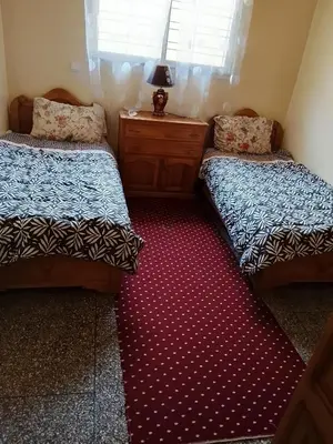 a bedroom with two beds and a red carpet at Razzak in Rabat