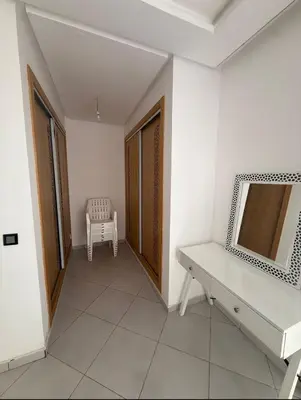 a hallway with a desk and a chair in a room at Apartment avec piscine terrasse et balcon in Bouznika