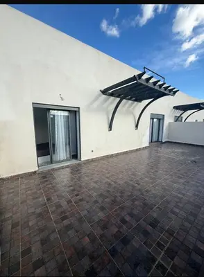 a white building with a patio with an umbrella at Apartment avec piscine terrasse et balcon in Bouznika