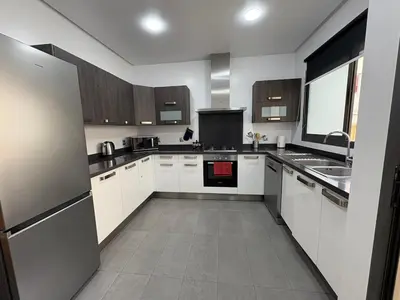 a large kitchen with white cabinets and a sink at Premium 2 Bedroom Suite Maarif Central & High-Speed Wi-Fi Fully Equipped Walk to Twin Center & Shops Next to Carrefour Val Fleuri Family-Friendly in Casablanca