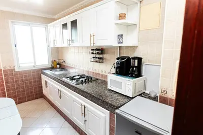 a small kitchen with white cabinets and a microwave at Apartement complets pres Ocean port de Casablanca in Casablanca