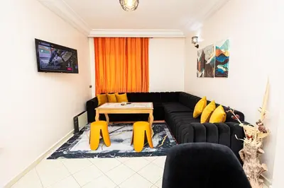 a living room with a black couch and yellow chairs at Apartement complets pres Ocean port de Casablanca in Casablanca