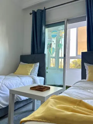 a room with two beds and a table and a window at Charming apartment near Mohammedia station in Mohammedia