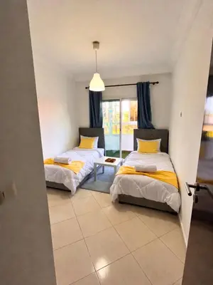 two beds in a room with a window at Charming apartment near Mohammedia station in Mohammedia