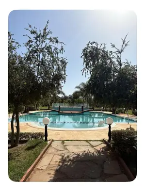 a swimming pool with two white umbrellas in front of it at La Hacienda De Morafia in Bouskoura