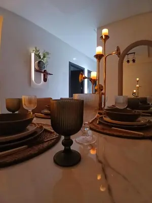a dining room with plates and wine glasses on a table at Appartement la siesta beach resort in Mohammedia