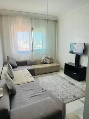a living room with a couch and a flat screen tv at Appartement la siesta beach resort in Mohammedia