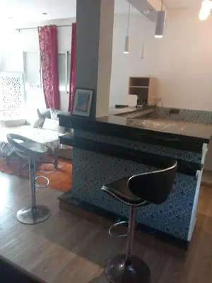 a kitchen and living room with a counter and chairs at Suite in nice résidence in Rabat