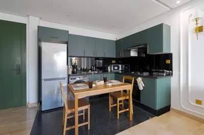 a kitchen with green cabinets and a wooden table and chairs at Cosy and charming studio - parking & Terasse in Maarif