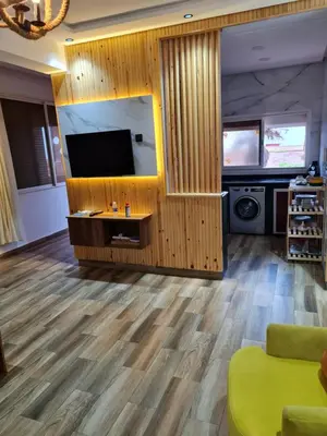 a living room with a flat screen tv and wooden floors at Adnani in Temara