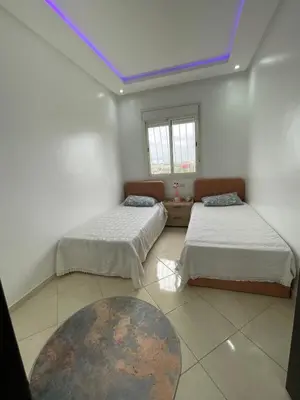 two beds in a room with a blue ceiling at Apparemment Moderne à Temara in Temara