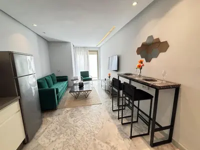 a kitchen and living room with a bar and a green couch at Seabreeze home on the Corniche in Casablanca