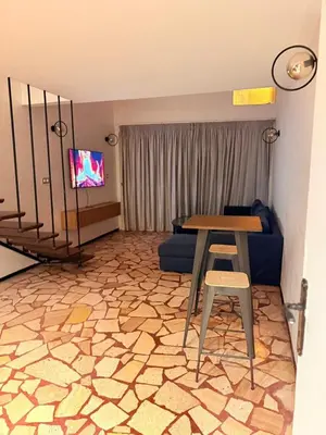 a living room with a table and a chair and a tv at Beautiful modern duplex - comfortable, good location in Casablanca