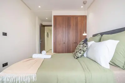 a bedroom with a green bed with a wooden door at Dynasty Estate Apartment Maarif with Parking Netflix Air Conditioning in Casablanca