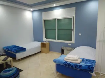 a blue room with two beds and a window at Studios Taha in Rabat