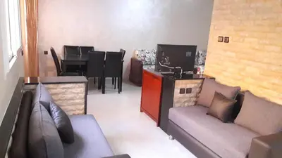 a living room with couches and a kitchen and a table at Reem in Temara