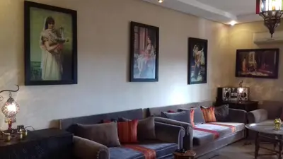 a living room with couches and paintings on the wall at Perle de Tamaris in Dar Bouazza