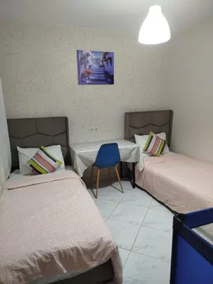 a room with two beds and a blue chair at appartement plage Bouznika in Bouznika