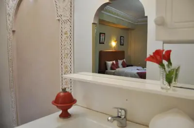 a bathroom with a sink with a mirror and a bed at Riad Hamdani in Casablanca