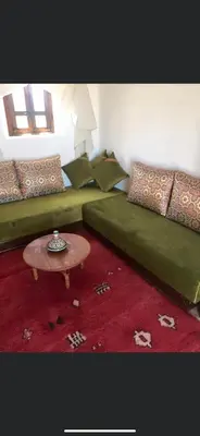 a bedroom with a green bed and a table at Safa Boulaouane in Douar Annbirat