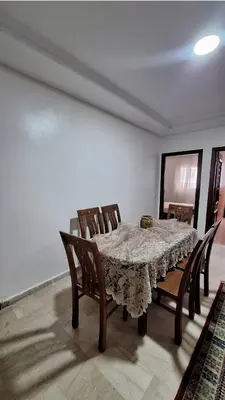 a dining room table with wooden chairs and a table cloth at Agdal Two-Bedroom Apartment 2 Minutes from Agdal Train Station in Rabat