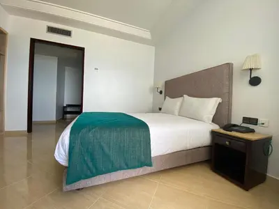 a bedroom with a bed with a green blanket on it at Hotel Azur in Casablanca