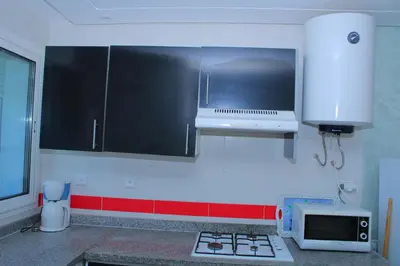 a kitchen with black and white cabinets and a microwave at Jnane Eddalya in Bouznika